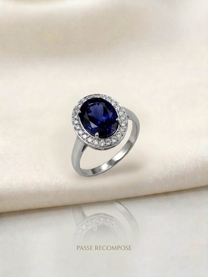 Bague en or gris ornée d'un saphir bleu ovale entouré de diamants